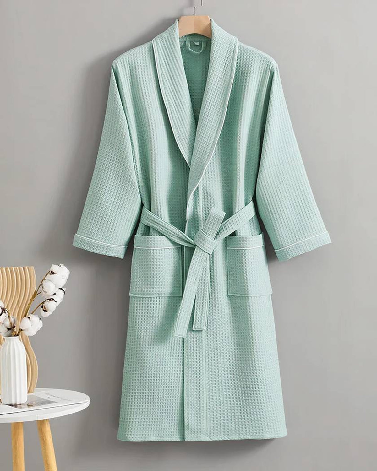 Peignoir en coton gaufré vert d'eau sur cintre, col châle à passepoil blanc et ceinture nouée