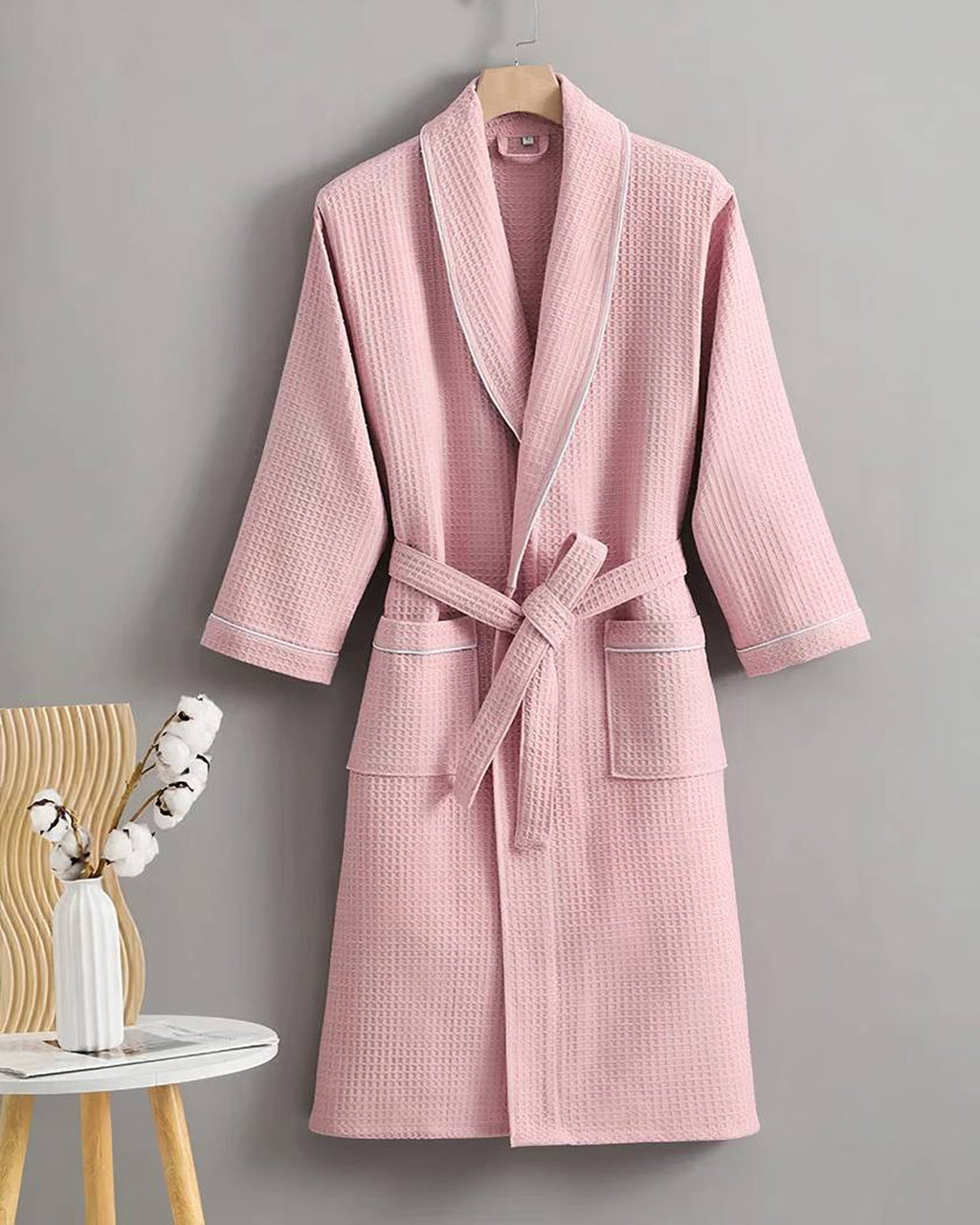Peignoir en coton gaufré rose poudré sur cintre, col châle à passepoil blanc et ceinture nouée