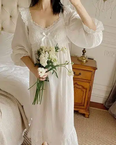 femme dans une chambre portant une chemise de nuit blanche en coton, avec de la dentelle et un bouquet de fleurs