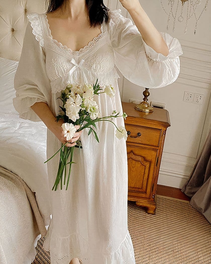 femme dans une chambre portant une chemise de nuit blanche en coton, avec de la dentelle et un bouquet de fleurs