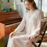 Femme blonde avec une nuisette blanche transparente assise sur une chaise en bois devant un piano
