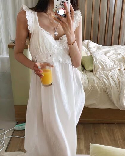 Femme brune portant une nuisette blanche en dentelle dans une chambre un verre de jus d'orange a la main