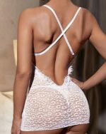 Femme de dos portant une nuisette en dentelle blanche à motifs dans une chambre.