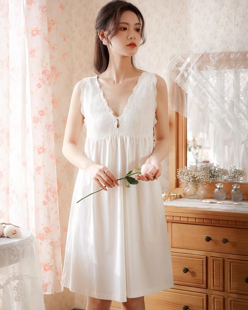 Femme asiatique debout en nuisette blanche portant une fleur rose à la main