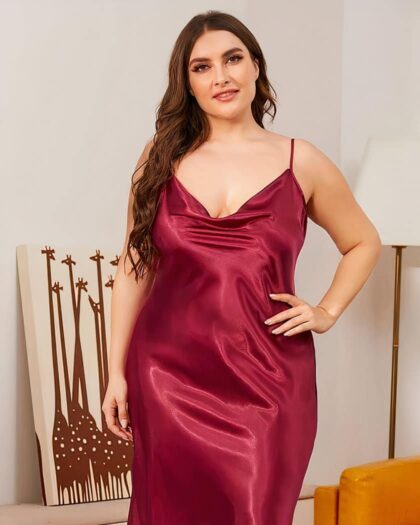 Femme portant une nuisette grande taille longue en soie rouge dans un salon à côté d'un fauteuil en cuir.