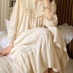 Femme assise sur un lit en robe de nuit beige