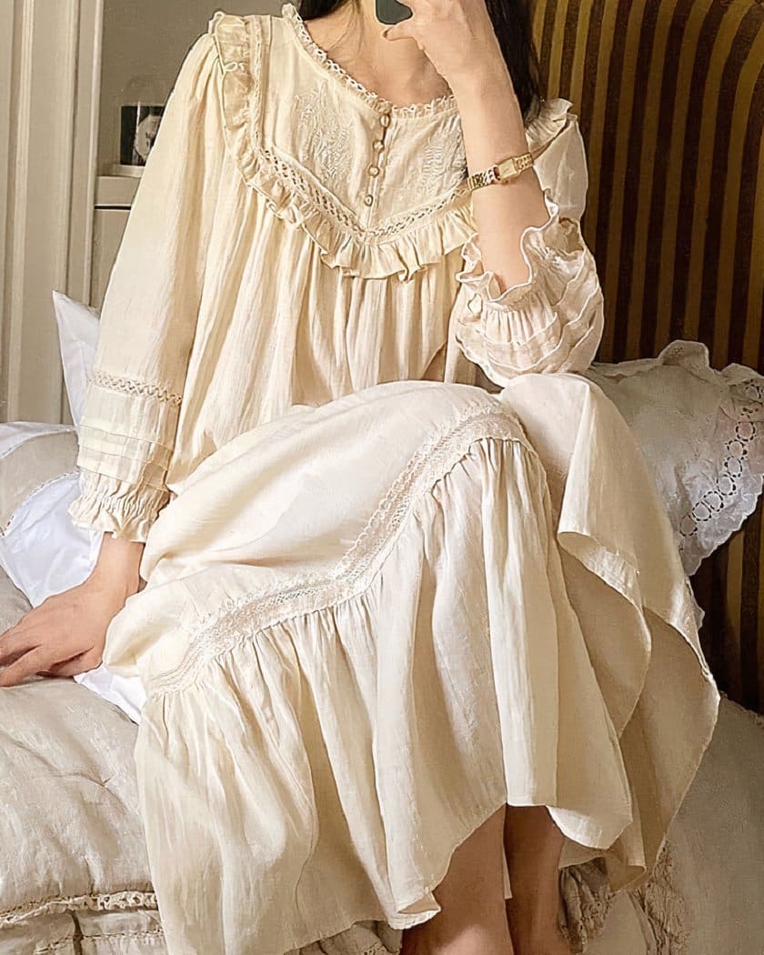 Femme assise sur un lit en robe de nuit beige