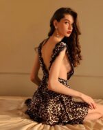 Femme châtain assise à genoux sur un lit portant une nuisette motif léopard.