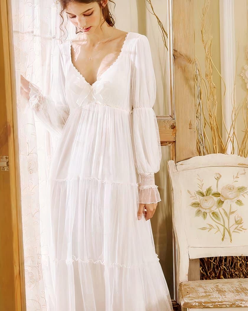 Photo d'une femme portant une nuisette blanche à coté d'un rideau