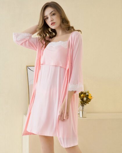 Nuisette grossesse avec kimono de couleur rose, portée par une femme debout dans une salle aux murs jaunes