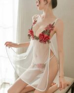 Femme agenouillée portant une nuisette blanche transparente avec des fleurs brodées sur la poitrine