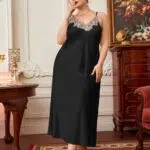 Nuisette grande taille de couleur noire avec de la dentelle, portée par une femme debout dans une pièce luxueuse