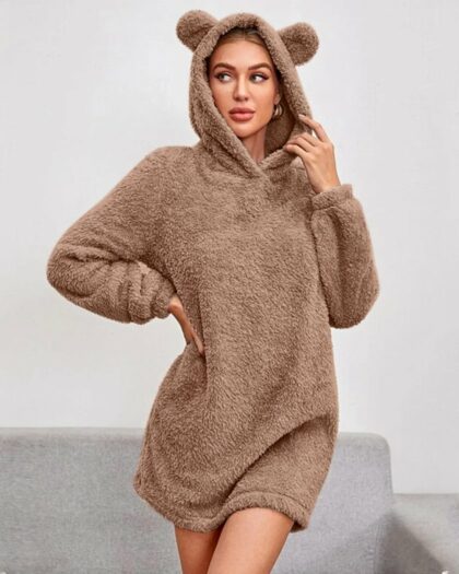 Chemise de Nuit Femme Hiver avec Capuche en Forme d'Ours portée par une femme devant un canapé et un mur gris