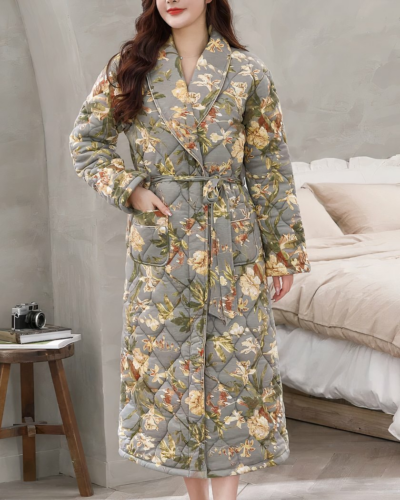 Robe de Chambre Matelassée avec Imprimé Floral portée par une femme avec des murs gris un lit et une petite table derrière