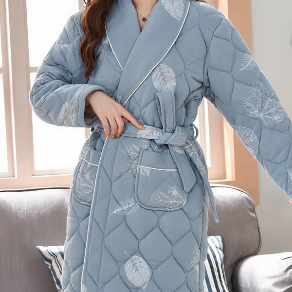 Robe de Chambre Matelassée avec Imprimé en Forme de Plume portée par une femme avec un canapé et une fenêtre derrière elle