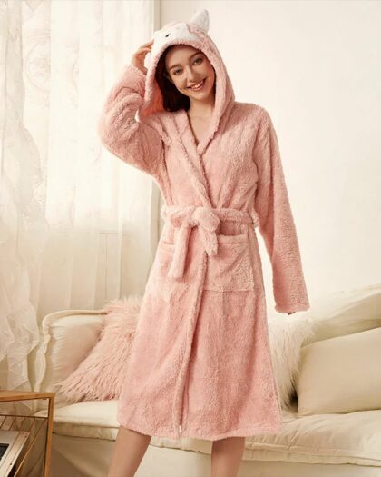 Robe de Chambre Capuche en Forme d'Animal avec des Oreilles portée par une femme devant un canapé avec des coussins et des rideaux et une petite table à gauche