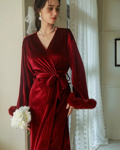 Robe de Chambre de Luxe Élégante et Épaisse Rouge, porté par une femme, avec ourlets des manches longues en fausse fourrure.