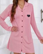 Robe de Chambre Boutonnée Rose avec Col à Revers Cranté avec un imprimé coeur noir, porté par une femme.