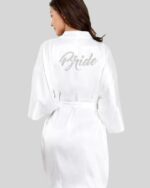 Une femme de dos portant un peignoir blanc avec écriture bride en strass