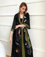 Jeune femme habillée en Peignoir kimono pour femme avec motif à fleurs avec un arrière plans un mur blanc