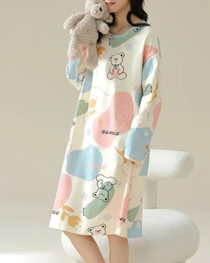 Jeune femme vêtue d'une chemise de nuit d'hiver blanc, rose, vert et bleu avec des motifs d'oursons.